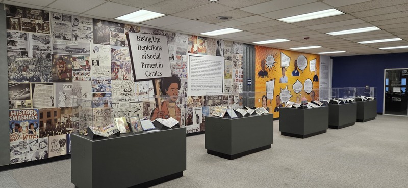 Image from the physical exhibit that shows display cases and wallpaper