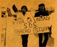 Dos manifestantes con un afiche. / Two protesters holding a sign.